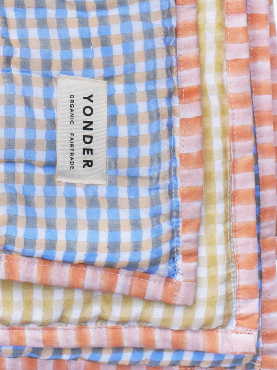 Stack of colorful checkered fabrics with a Yonder label on a blue background